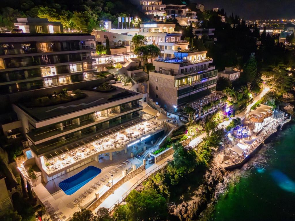 Elegants viesnīcas komplekss pie jūras, izgaismots naktī, ar baseinu un terasēm, kur viesi var baudīt ēdienu un skaistu skatu. Labi sakārtota teritorija ar zaļumiem un piekļuvi pludmalei.