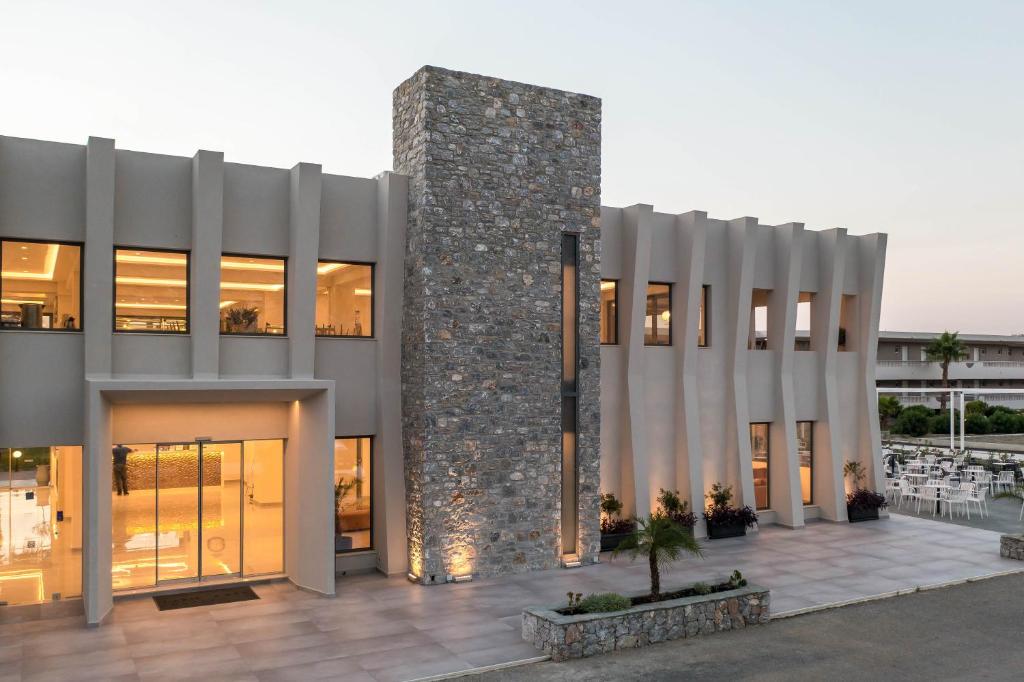 Modernā Lardos Bay viesnīca ar akmens sienām un plašu ieeju piekrastē.