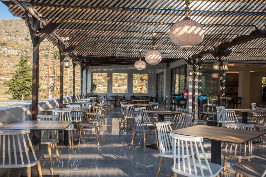 Lardos Bay viesnīcas terase ar moderniem galdiem un krēsliem piekrastē.