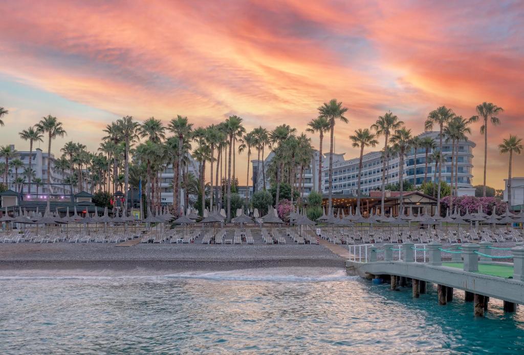 Meryan Hotel piekrastes zona ar palmām un saulrietu.