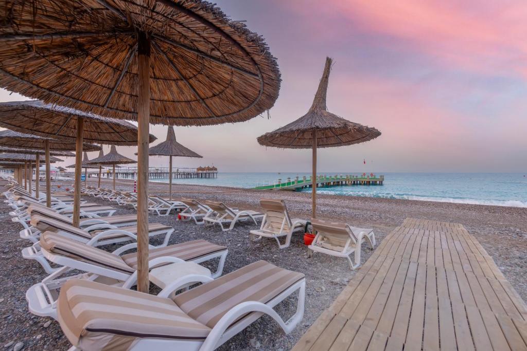 Meryan Hotel pludmales zona ar sauļošanās krēsliem un saulessargiem piekrastē.