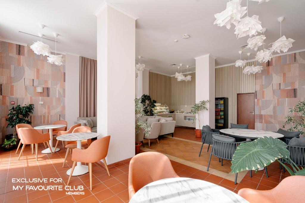 Mūsdienīgs kafijas veikals ar gaišu interjeru, kurā ir eleganti galdi un krēsli, kā arī dekoratīvas gaismas. Telpā ir pieejami augi un saldumu vitrīna, radot patīkamu atmosfēru apmeklētājiem.