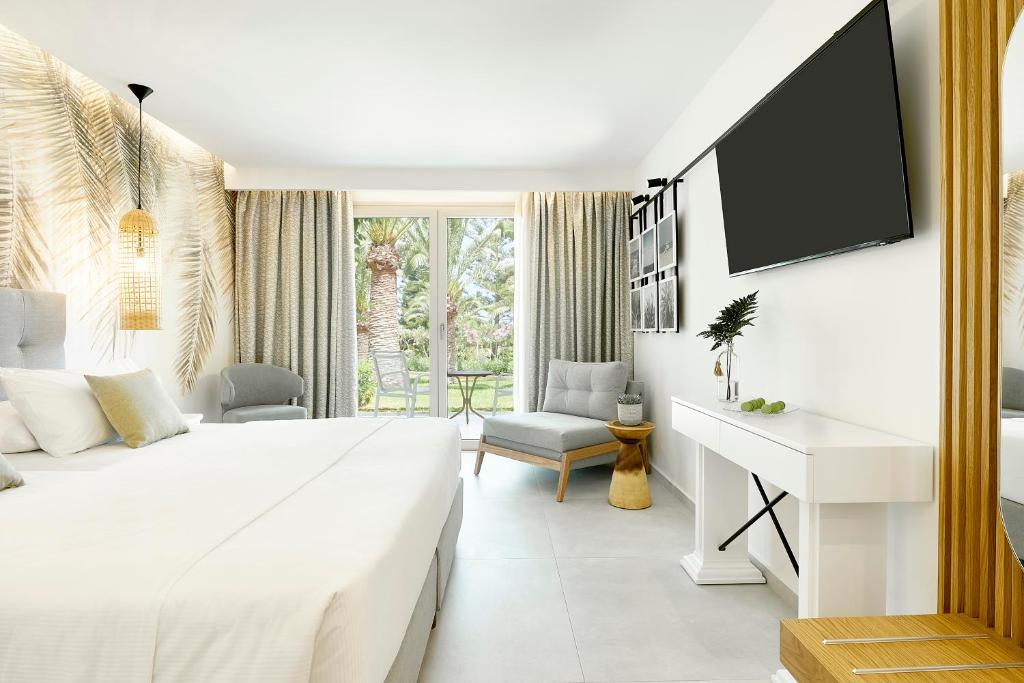 Mūsdienīga guļamistaba ar gaišām krāsām, augstiem griestiem un lieliem logiem, kas nodrošina skatu uz dārzu. Interjerā ir tropiski motīvi, ērtas mēbeles un stilīgs televizors.