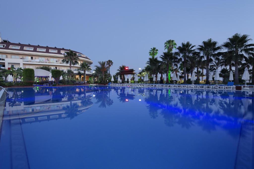Saphir Hotel & Villas baseins ar palmām piekrastē pie saulrieta