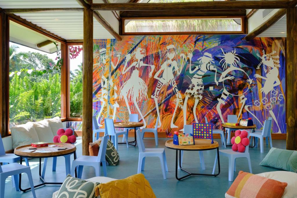 Krāsaina un modernā telpa ar māksliniecisku sienu gleznojumu, kas attēlo dejotājus, un ērtām mēbelēm, ideāli piemērota atpūtai un radošām aktivitātēm. Interjers apvieno spilgtas krāsas un dabīgu apgaismojumu, radot draudzīgu atmosfēru.