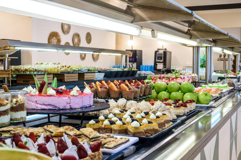 Bagātīgs deserts bufete ar dažādām kūkām, augļiem un saldējumiem, kas izkārtoti uz elegantas galda virsmas.