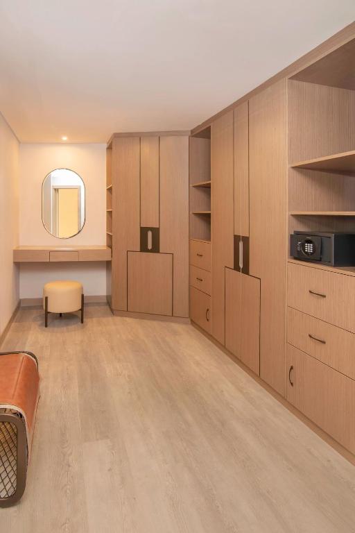 Mūsdienīgs viesnīcas numurs ar koka skapjiem, elegantu spoguli un minimālistisku dizainu. Telpa ir gaiša un plaša, nodrošinot komfortablu atmosfēru.