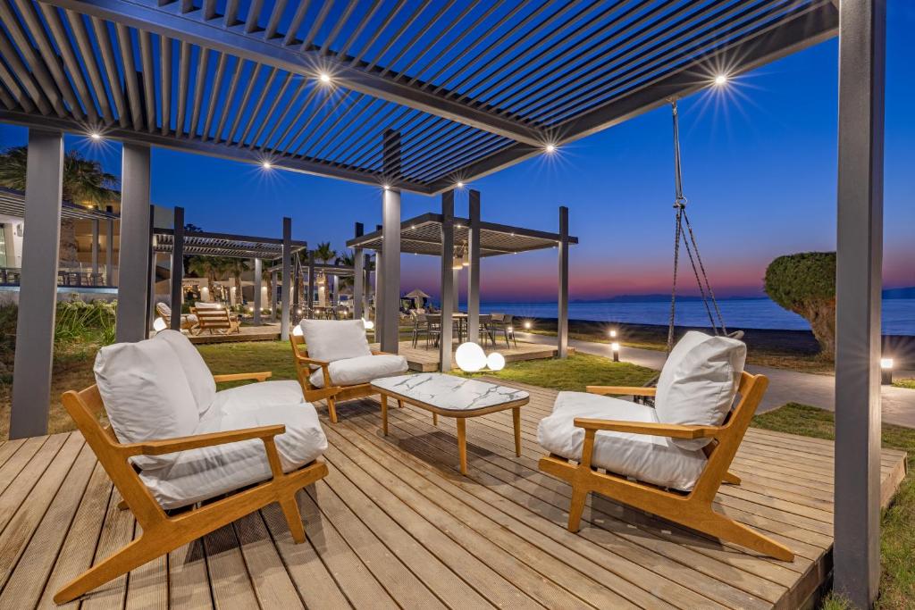 Mūsdienīga atpūtas zona pie Sun Beach Resort ar koka krēsliem un saulrietu fonā.