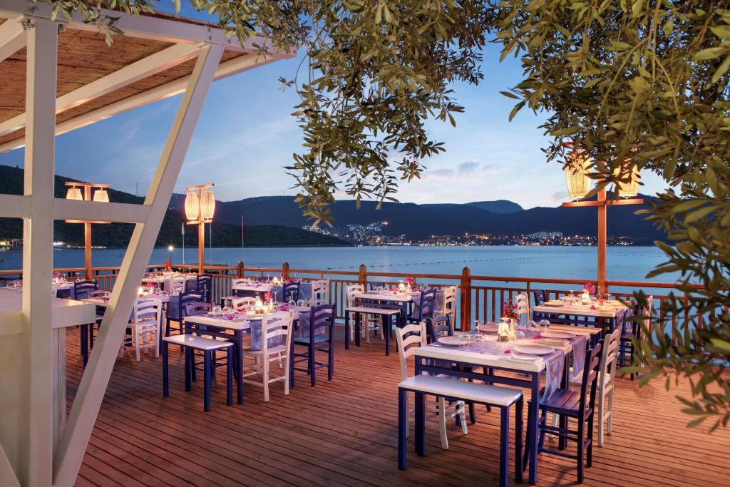 Restorāns pie ūdens DoubleTree by Hilton Bodrum Isil Club Resort ar romantiskām gaismām.