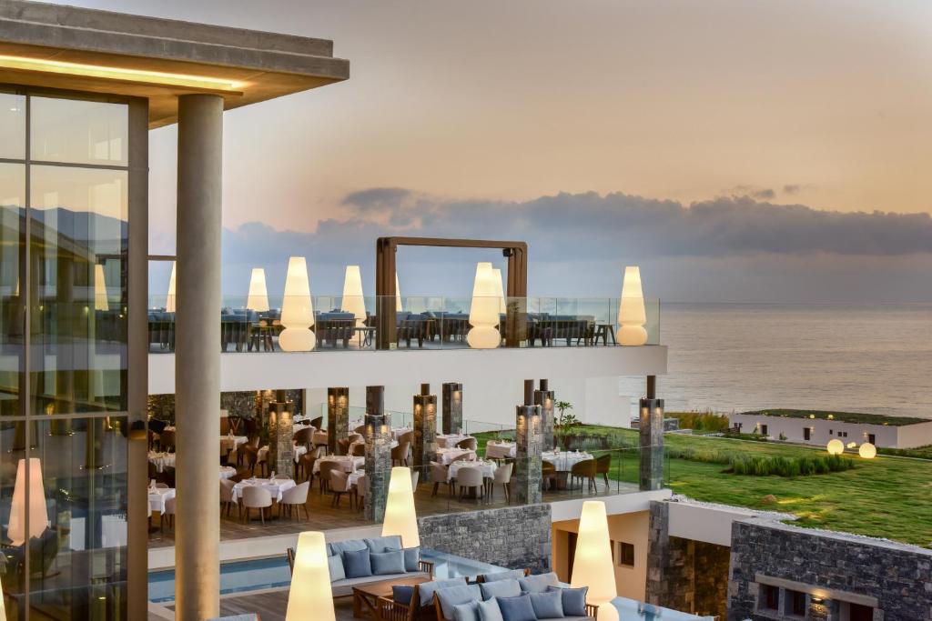 Mūsdienīgs restorāns ar skatu uz jūru, apgaismots ar stilīgām lampām un elegantām ēdamzālēm. Ideāla vieta romantiskām vakariņām saulrietā.