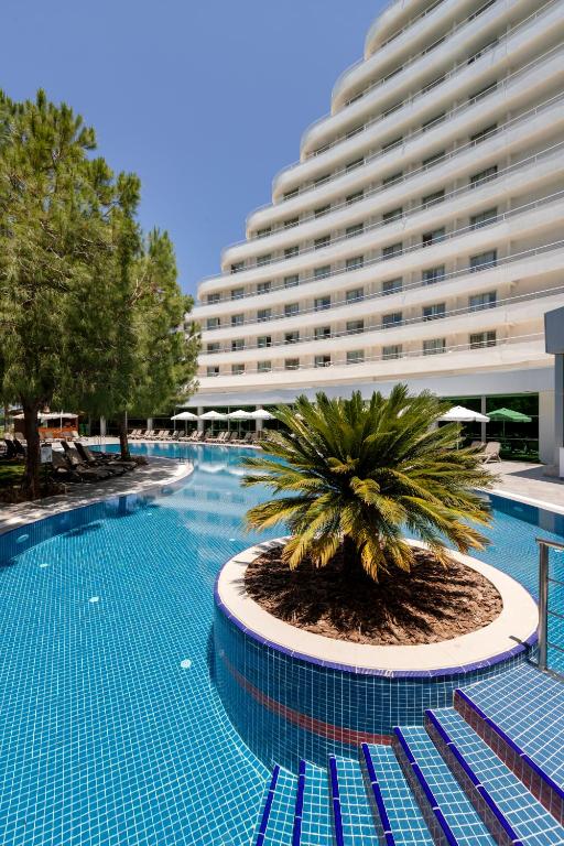 Miracle Resort Hotel baseins ar palmām un sēdvietām piekrastē