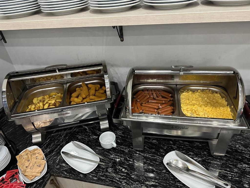 Svaigu ēdienu bufete ar ceptiem kartupeļiem, desiņām, rīsiem un uzkodām. Metāla traukos sakārtoti dažādi ēdieni, gatavi pasniegšanai.