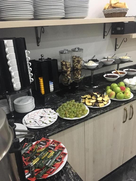 Brokastu galds ar dažādiem ēdieniem, tostarp augļiem, jogurtu un maizes izstrādājumiem, kā arī kafijas un tējas piedevām. Ideāla izvēle rīta maltītei.