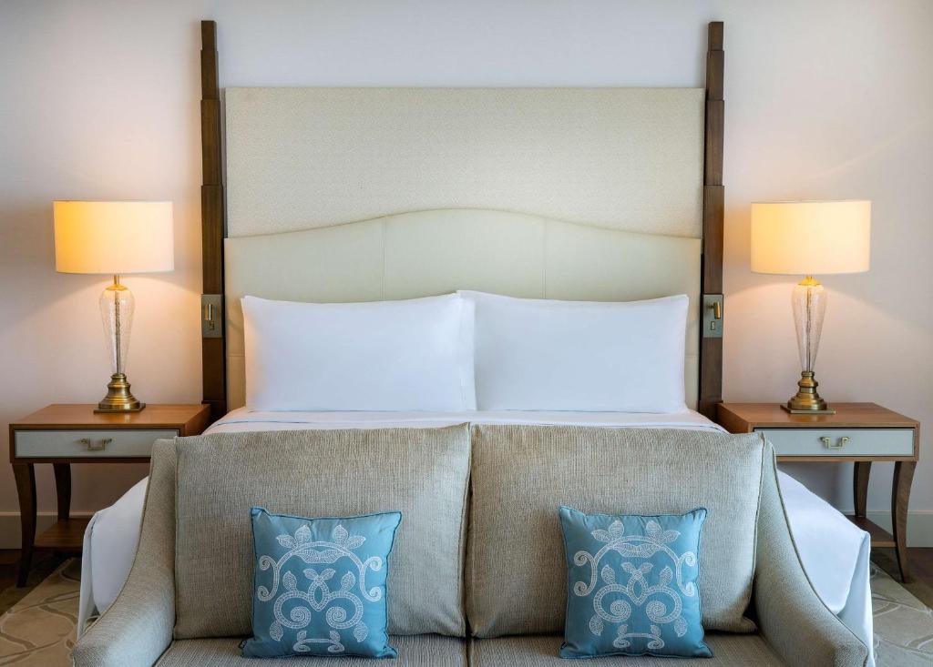 Mūsdienīga guļamistaba ar ērtiem gultas veļas izstrādājumiem, blakus esošām lampām un dekoratīviem spilveniem. Eleganta un relaksējoša atmosfēra.