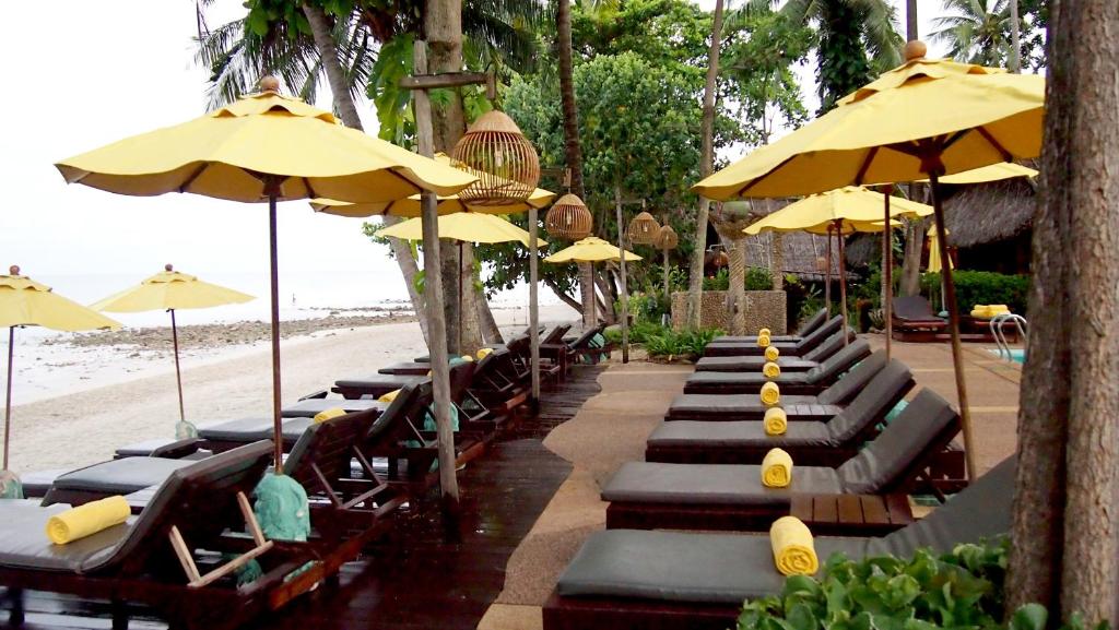 Atpūtas gultas piekrastē ar dzelteniem saulessargiem Banpu Koh Chang