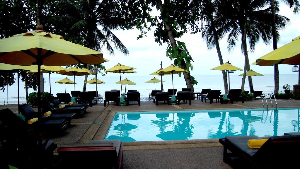 Viesnīcas Banpu Koh Chang baseins ar dzeltenām saules parasolēm piekrastē