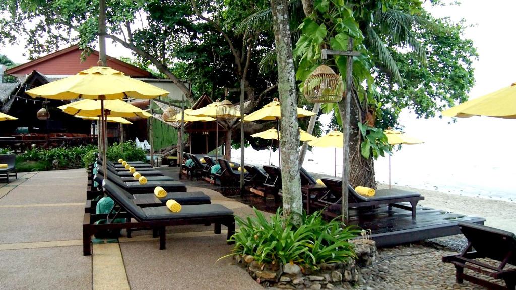 Sauļošanās krēsli pie pludmales ar dzeltenām saulessargiem, Banpu Koh Chang
