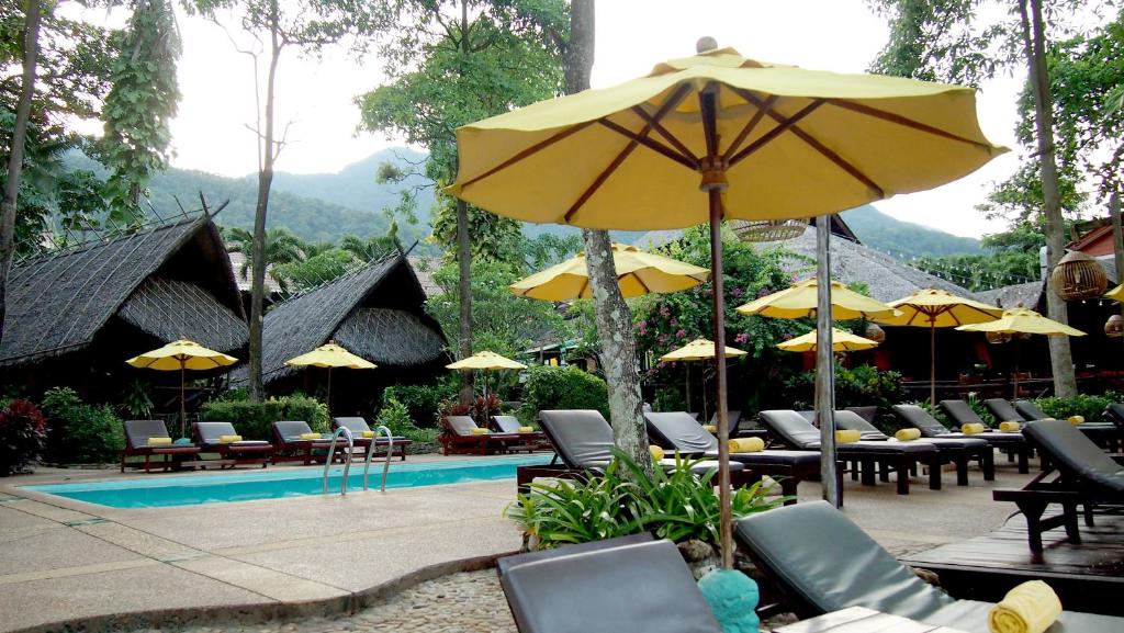 Peldbaseins ar dīvāniem un saules paranām viesnīcā Banpu Koh Chang.
