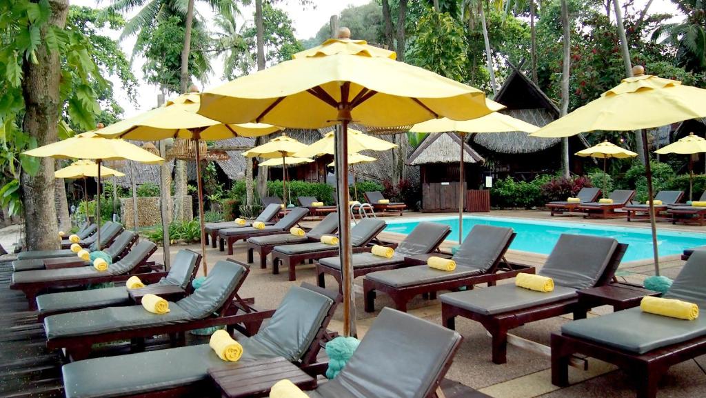 Atpūtas zona pie baseina viesnīcā Banpu Koh Chang ar dzelteniem saulesvārtiem.