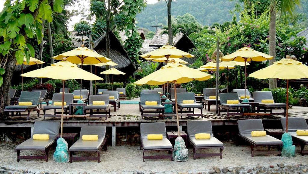 Sauļošanās krēsli ar dzeltenām saules segām pie Banpu Koh Chang.