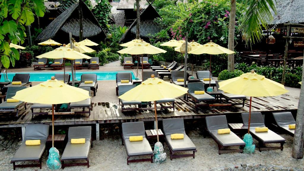 Peldbaseins un sauļošanās krēsli pie Banpu Koh Chang, tropiska vide.
