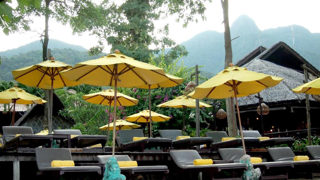 Sauļošanās krēsli ar dzelteniem saulessargiem pie Banpu Koh Chang