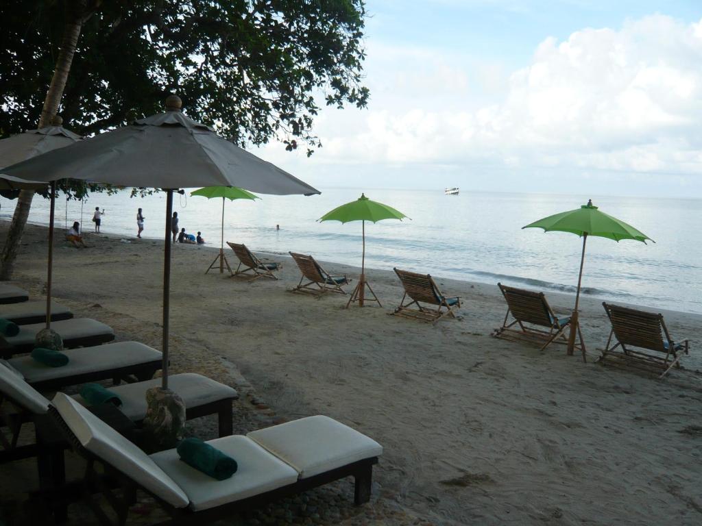 Pludmales zona ar sauļošanās krēsliem un zaļiem saulessargiem pie Banpu Koh Chang.