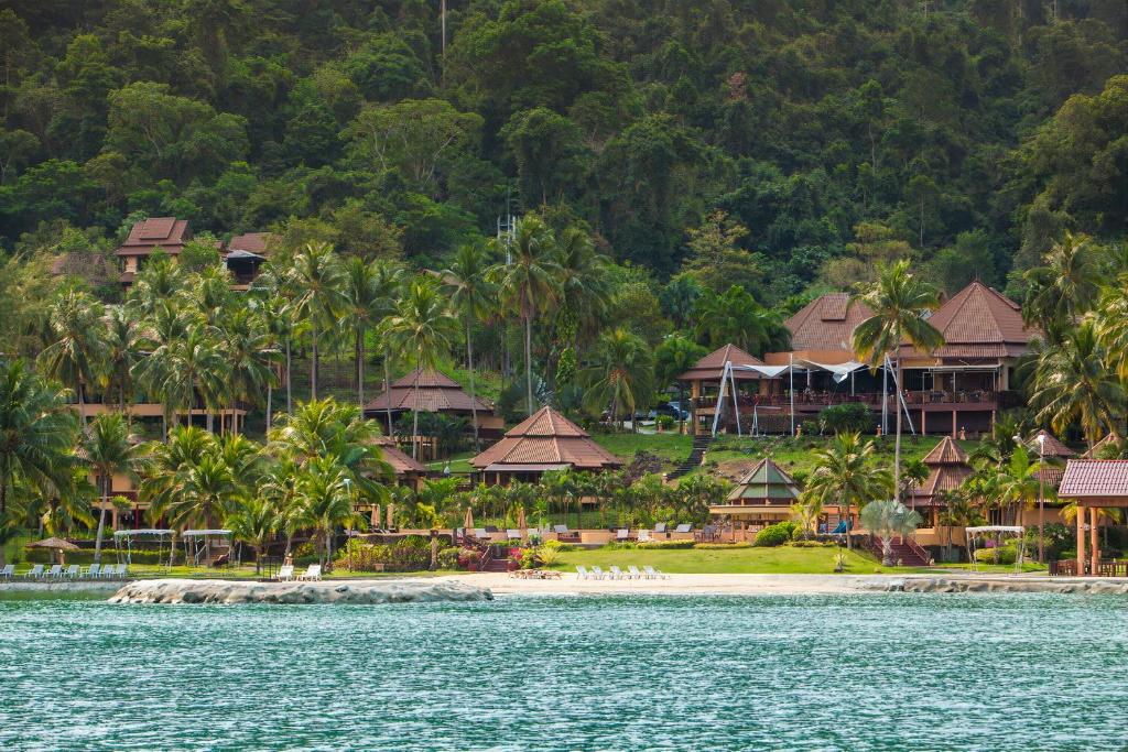 The Aiyapura Koh Chang Resort piekrastē, ar tropu ainavu un palmām.