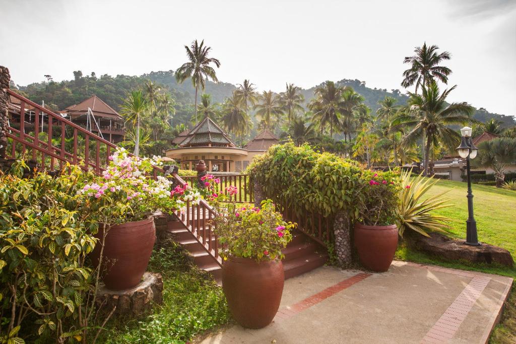 Labi apzaļumota ieeja pie The Aiyapura Koh Chang Resort ar ziediem un palmām.