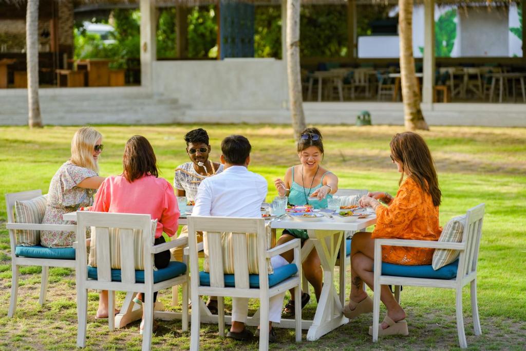 Viesi bauda maltīti Ifuru Island Maldives dārzā.