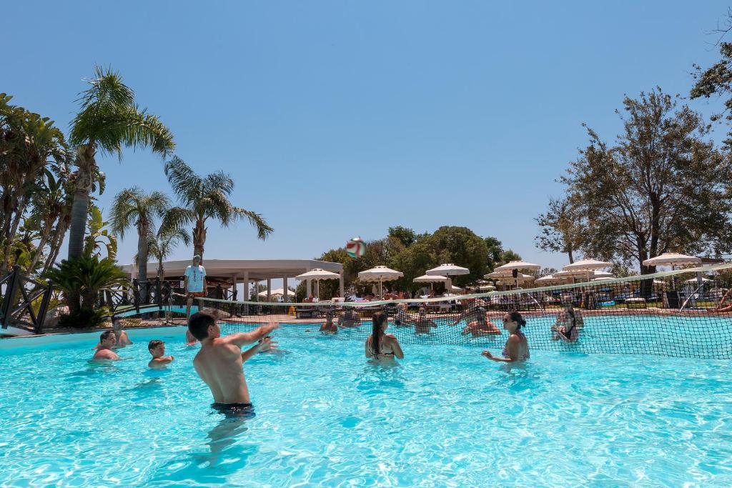 Viesnīcas Calypso Beach peldbaseins ar cilvēkiem, kas spēlē volejbolu.