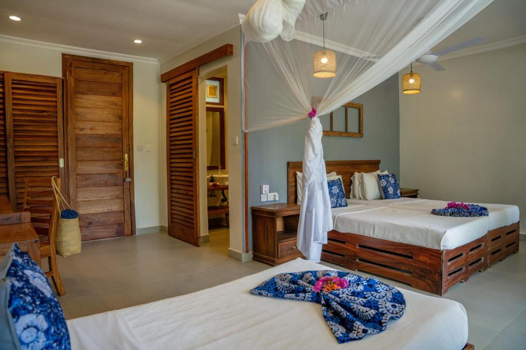 Grezns numurs Michamvi Sunset Bay ar divvietīgām gultām un koka mēbelēm.