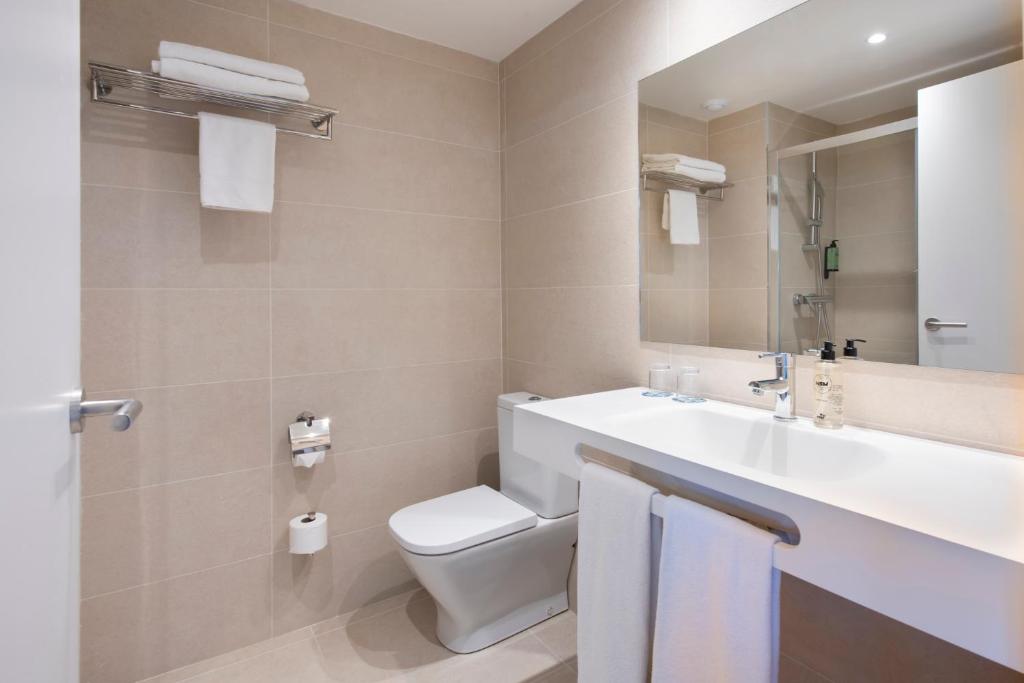 Mūsdienīgs vannas istabas interjers ar gaišām flīzēm, plašu izlietni un spoguli, kā arī tualeti un dušas kabīni. Vannas istabā ir pieejami dvieļi un higiēnas līdzekļi.