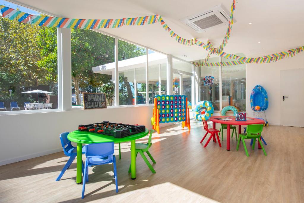 Bērnu spēļu istaba ar košām mēbelēm, dekoratīvām virtenēm un spēlēm, kas veidota patīkamai un priecīgai atmosfērai. Telpā ir daudz dabiskās gaismas un dažādi rotaļlietu elementi.