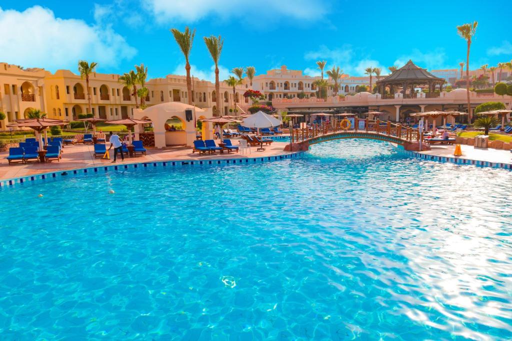 Charmillion Club Resort baseins ar saulainu debesi un palmām