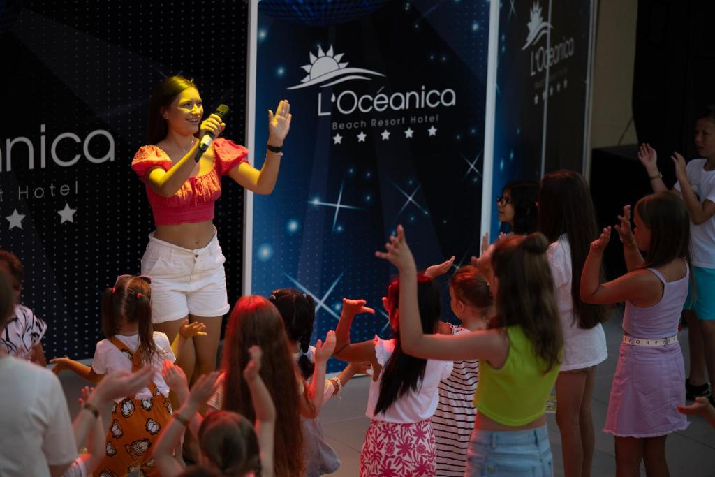 Bērni izbauda izklaidi L'oceanica Beach Resort Hotel, dziedot kopā ar izpildītāju.