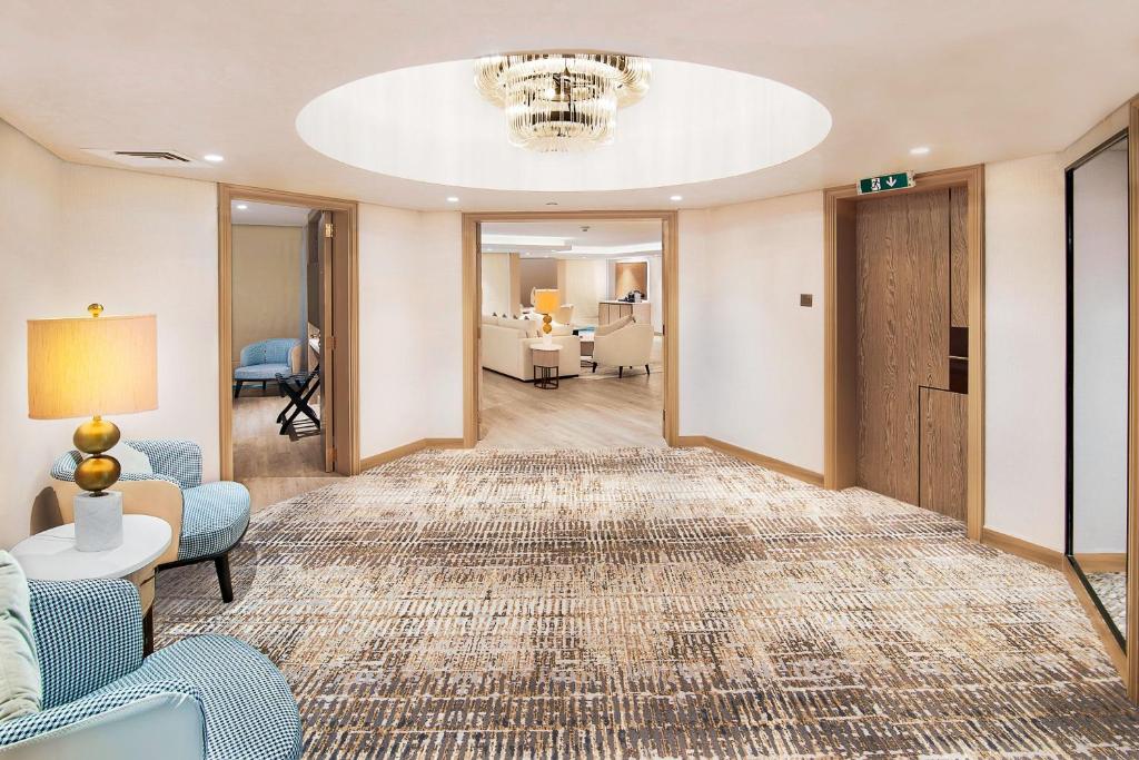 Mūsdienīgs un elegants viesnīcas vestibils ar plašu telpu, modernām mēbelēm un stilīgu apgaismojumu. Grīda ir klāta ar greznu paklāju, radot viesmīlīgu atmosfēru.