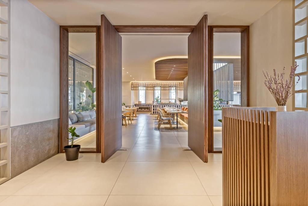 Mūsdienīga interjera gaida viesus ar plašām durvīm, kas ved uz elegantu ēdamzāli un relaksācijas zonu, kurā ir dabas elementi un mīkstas mēbeles.