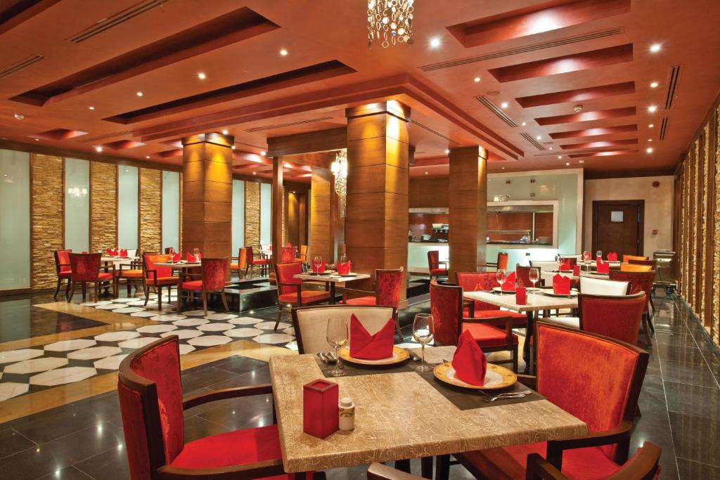 Elegantā ēdamzāle Sunrise Arabian Beach Resort ar sarkaniem krēsliem un modernu apgaismojumu.