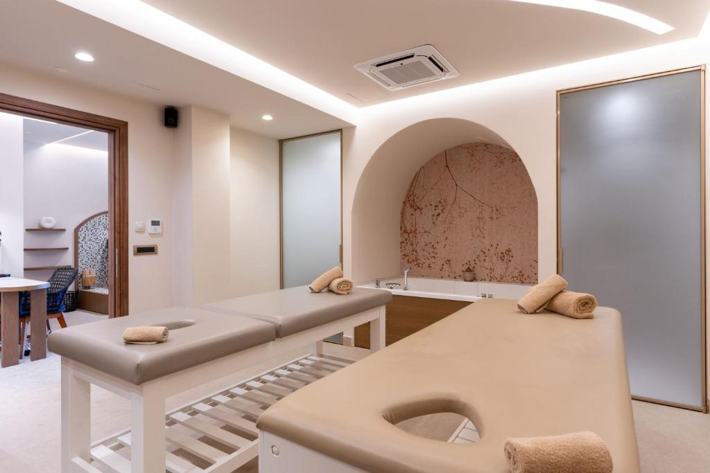 Moderns spa telpas interjers ar masāžas galdiem un relaksējošu atmosfēru. Telpā ir redzami dvieļi un eleganta apgaismojuma elementi.