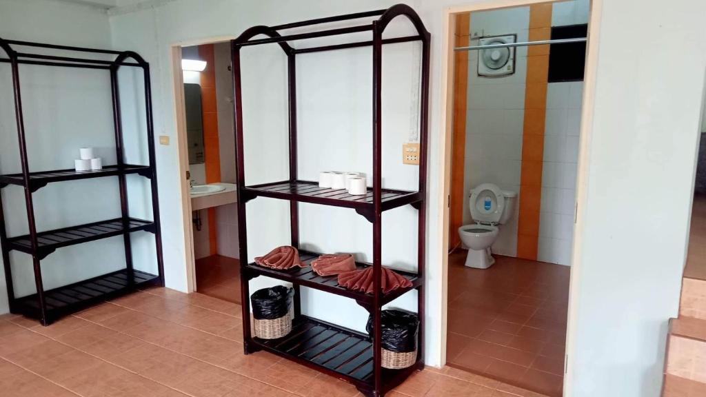 Telpa ar plauktiem, uz kuriem novietoti dvieļi un tualetes papīrs, ieejas durvis uz vannas istabu. 