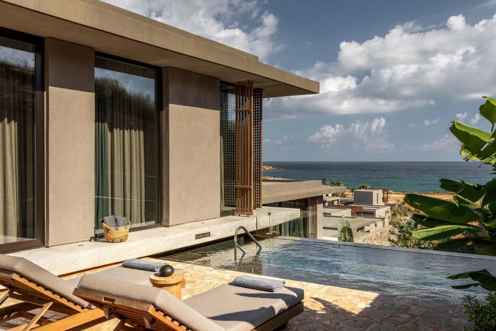 Luksusa pludmales viesnīcas terase ar baseinu un skatu uz jūru, apzaļumota ar palmām un mūsdienīgu arhitektūru. Ideāla vieta atpūtai un relaksācijai.