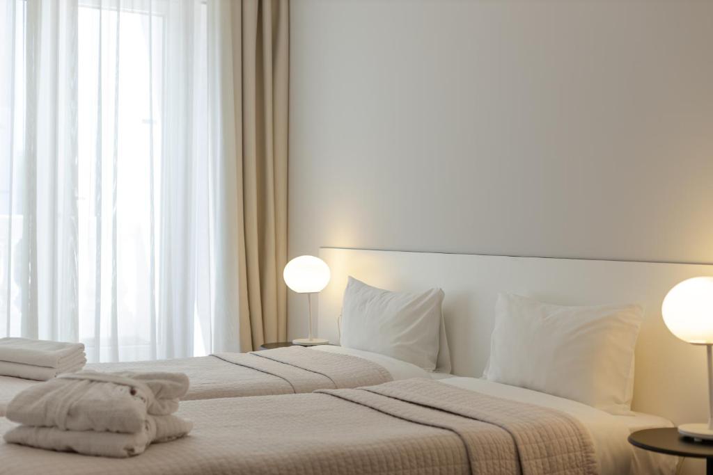 Gaiša un moderna guļamistaba ar divām gultām, mīkstiem spilveniem un elegantu apgaismojumu. Lielie logi ar aizkariem nodrošina dabīgu gaismu un komfortablu atmosfēru.