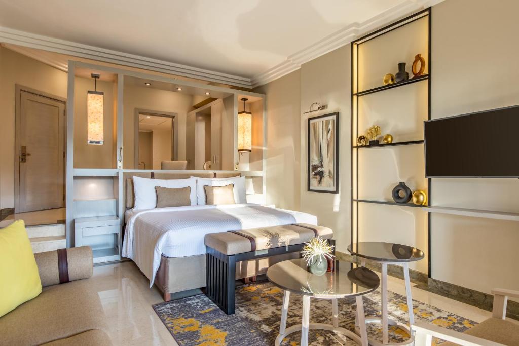 Mūsdienīgs viesnīcas numurs ar ērtu gultu, sēdvietām un elegantu interjeru, kas ietver televizoru un dekoratīvus elementus. Ideāla vieta relaksācijai un atpūtai.