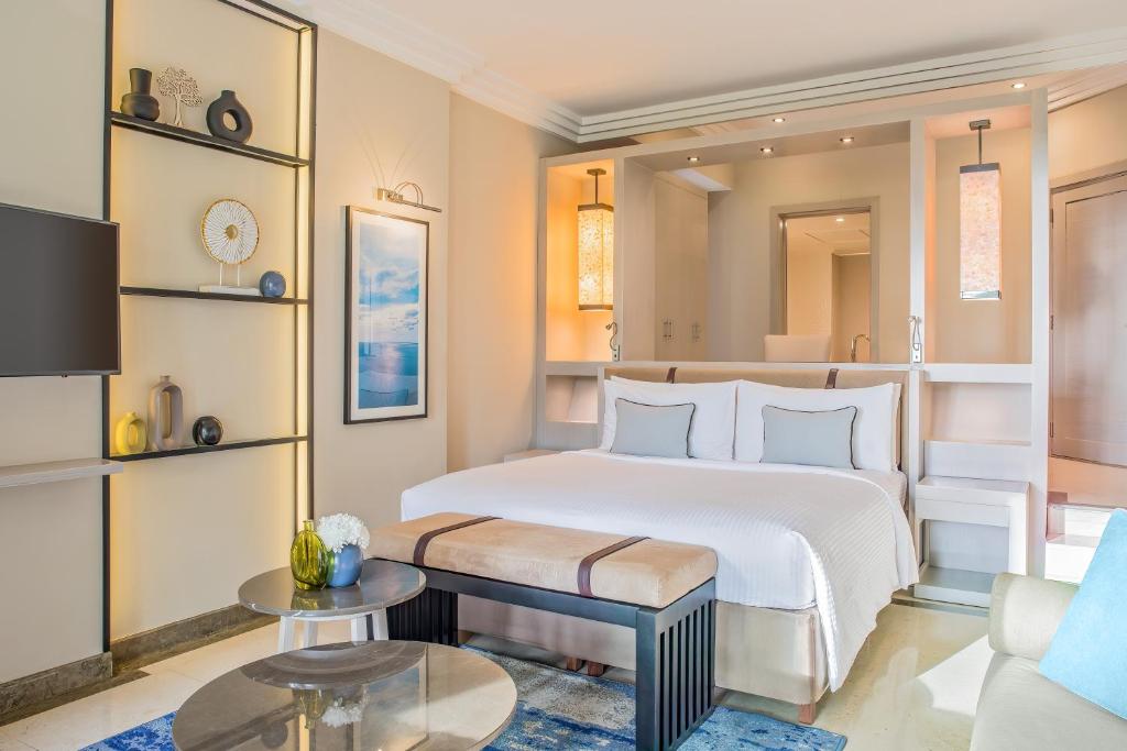 Mūsdienīgs guļamistabas interjers ar ērtu gultu, modernām mēbelēm un dekoratīviem elementiem. Telpa ir gaiša un eleganta, nodrošinot patīkamu atmosfēru.