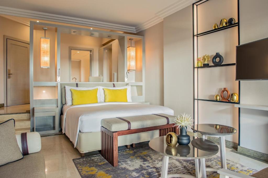 Mūsdienīga viesnīcas numura interjers ar ērtu gultu, dekoratīviem spilveniem un stilīgiem gaismas elementiem. Telpā ir moderna mēbeles un dekorācijas, kas rada patīkamu atmosfēru.