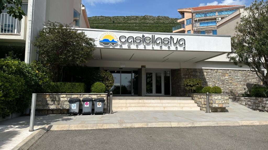 Ieeja viesnīcā Castellastva ar modernu arhitektūru un zaļiem apstādījumiem, atrodas kalnu apvidū. Pie ieejas redzami atkritumu konteineri.