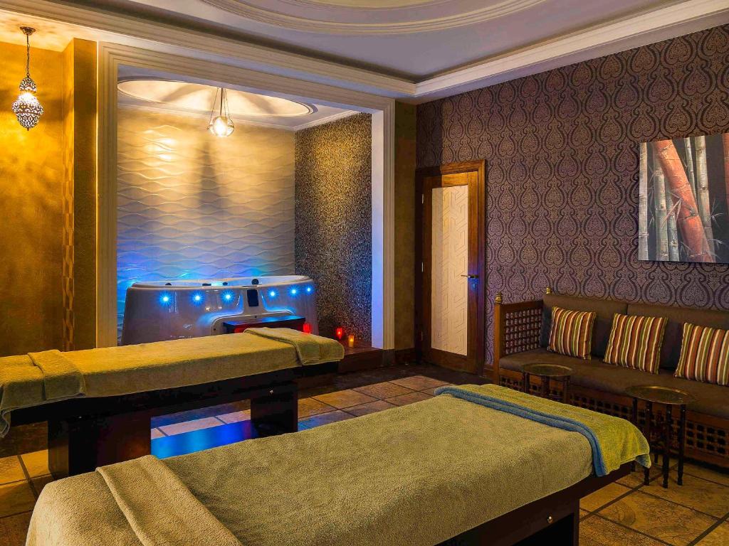 Mūsdienīga spa telpa ar masāžas galdiem un relaksējošu atmosfēru. Telpā ir burbuļvanna ar krāsainām gaismām un komfortabla sēdvieta atpūtai.