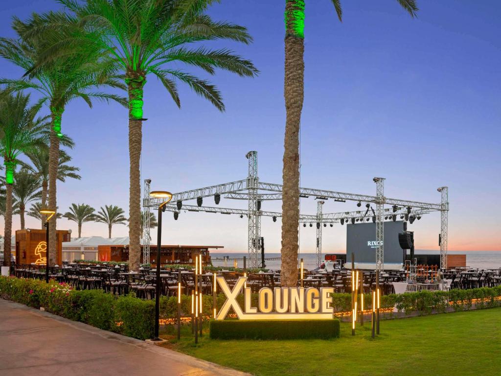 X Lounge piekrastes terase ar palmām un skatu uz jūru, ideāla vieta pasākumiem un relaksācijai, ar modernu apgaismojumu un izkārtojumu.