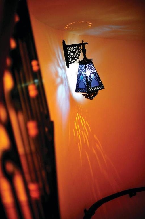 Skaista vintage lampa, kas izstaro gaismu un rada interesantas ēnas uz sienas. Elegants dizains piešķir telpai īpašu atmosfēru.